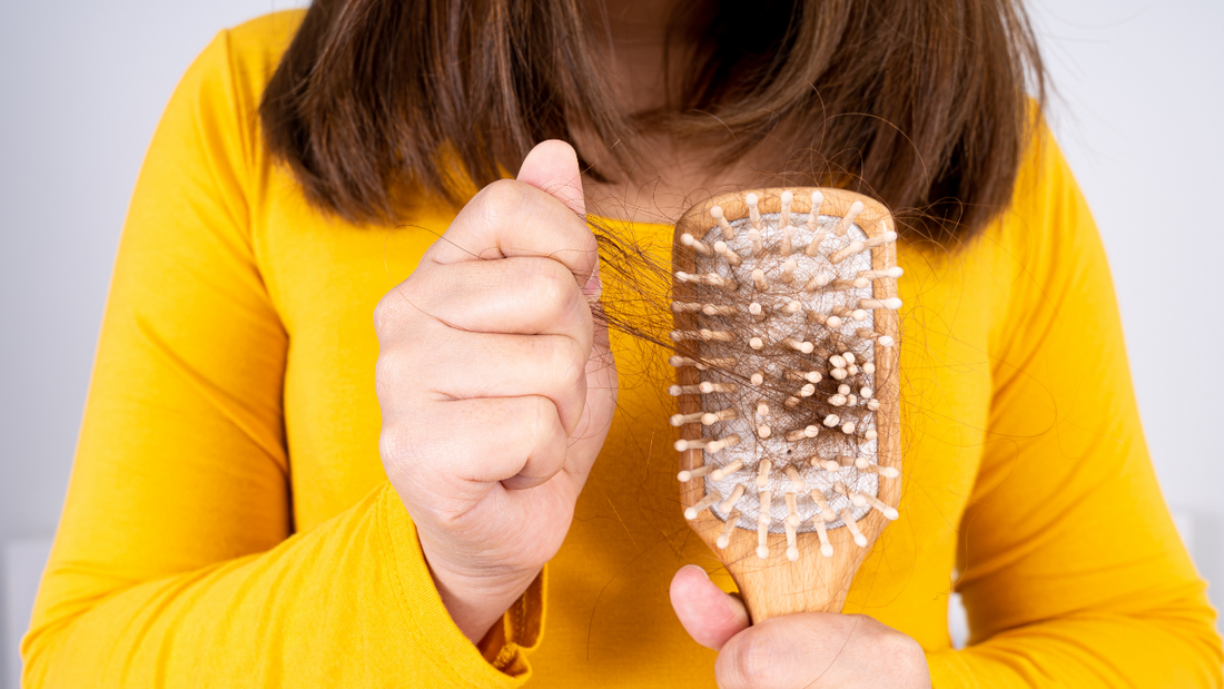 A woman pulling hair from a comb.