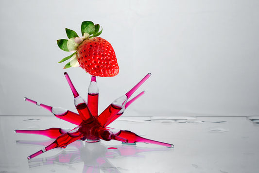 An abstract photo of a strawberry and a red fluid in a glass container. 