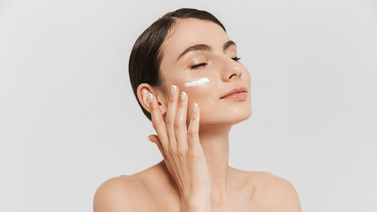 A woman applying a lotion to her upper cheek. 