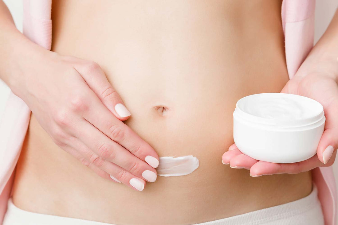 a photo of a woman applying peptide cream to abdomen.