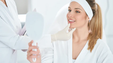 woman looking at self in mirror after a procedure