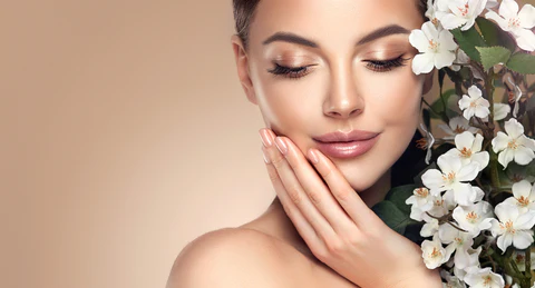 woman with hand to chin against flowers